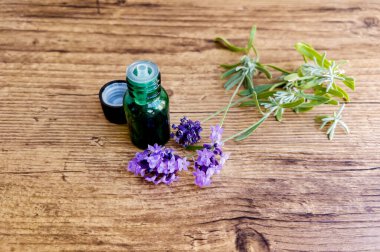 Lavanta yağı şişesi ve ahşap arka planda taze lavanta.