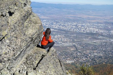 Sofya kentinin yukarısındaki sonbahar dağında yüksek bir kayada oturan bir kadın. Vitoşa Dağı, Bulgaristan