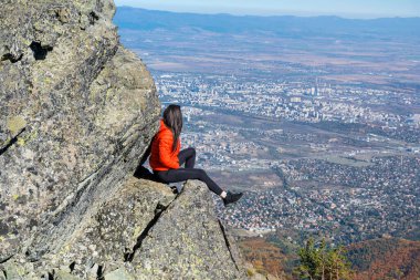 Sofya kentinin yukarısındaki sonbahar dağında yüksek bir kayada oturan bir kadın. Vitoşa Dağı, Bulgaristan