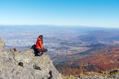 Sofya kentinin yukarısındaki sonbahar dağında yüksek bir kayada oturan bir kadın. Vitoşa Dağı, Bulgaristan
