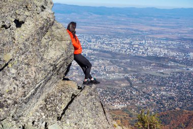 Sofya kentinin yukarısındaki sonbahar dağında yüksek bir kayada oturan bir kadın. Vitoşa Dağı, Bulgaristan