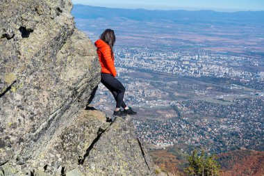 Sofya kentinin yukarısındaki sonbahar dağında yüksek bir kayada oturan bir kadın. Vitoşa Dağı, Bulgaristan