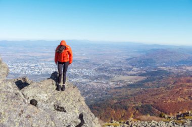 Sofya kentinin yukarısındaki sonbahar dağında yüksek bir kayada oturan bir kadın. Vitoşa Dağı, Bulgaristan