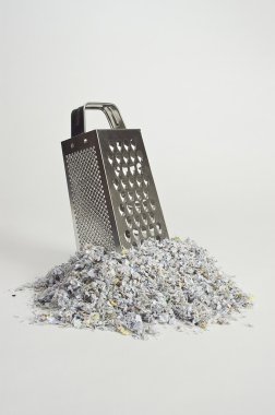 Cheese grater with paper shreds at the base clipart