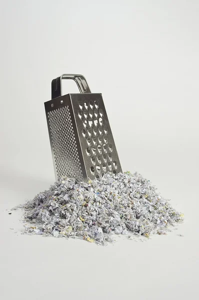 Cheese grater with paper shreds at the base — Stock Photo, Image