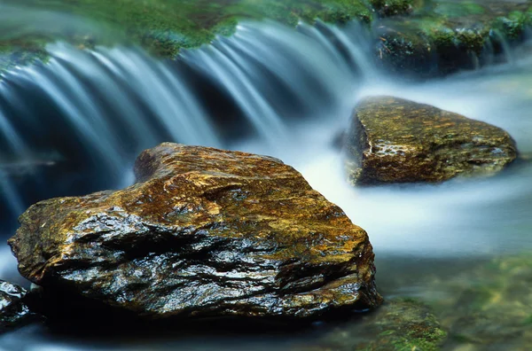 Små vattenfall och ett par river rocks Royaltyfria Stockbilder