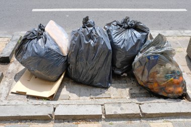 Sokak çöplüğünde bir sürü siyah çöp torbası.