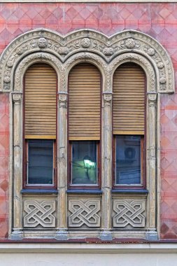 Kırmızı cepheli klasik tarz binasında üç kemerli pencere.