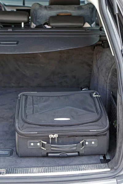 Black business luggage case in car cargo trunk