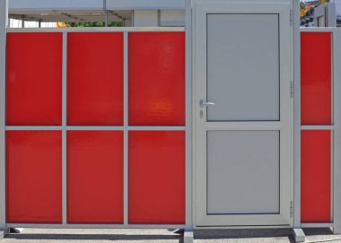Kırmızı duvarda alüminyum metalden yapılmış kapalı beyaz kapı