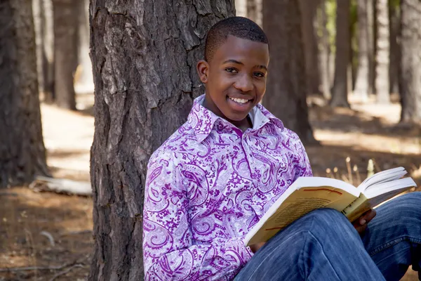 Africano adolescente chico leyendo un libro al aire libre — Foto de Stock
