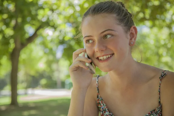 Leende ung flicka ringer på en mobiltelefon — Stockfoto