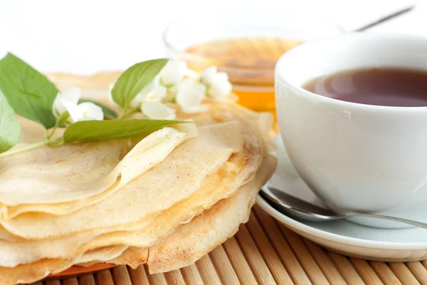 Pancakes with honey and black tea in a white cup — Stock Photo, Image