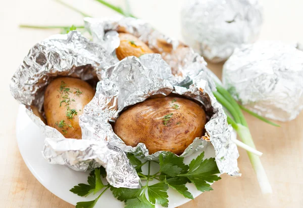 Vařené brambory v alobalu s bylinkami — Stock fotografie