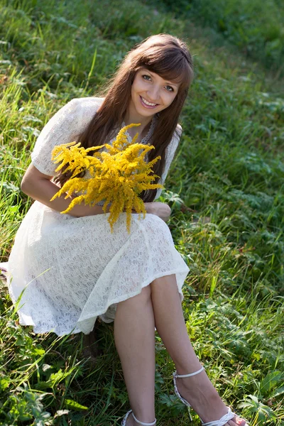 Woman with yellow flowers on a green lawn — Stock Photo, Image