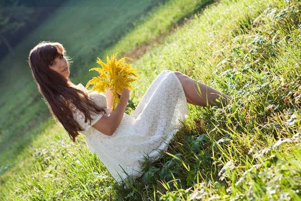 Girl with flowers sitting on the grass — Stock Photo, Image
