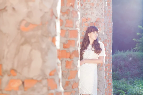 Pretty girl looks out the brick columns — Stock Photo, Image