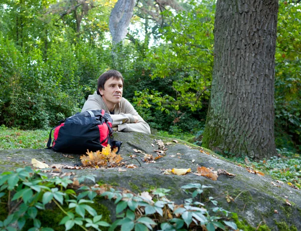 Hombre - una caída de turistas en el bosque sentado cerca de la piedra — Foto de Stock