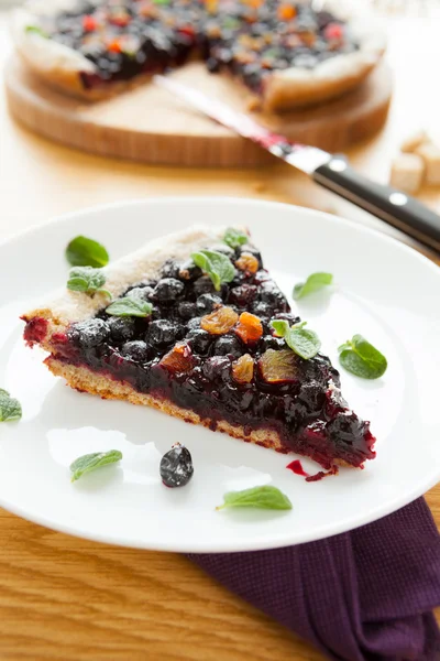 Stuk van berry taart op een witte plaat, blad oregano — Stockfoto