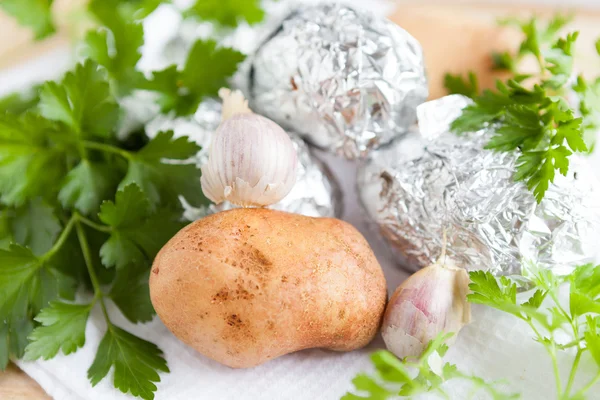 Raw potato close up and the potatoes in foil — Stock Photo, Image