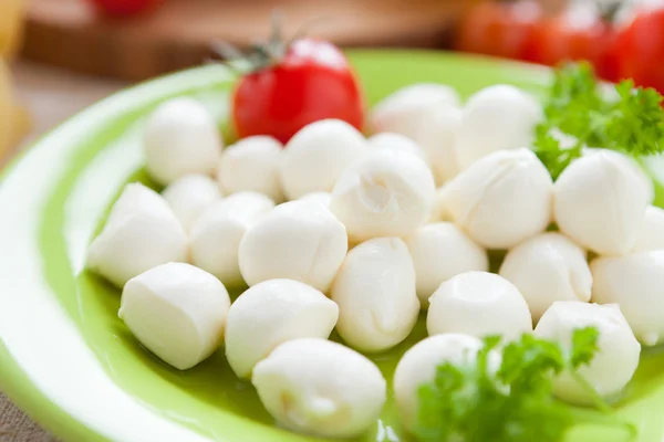 Kleine ballen van mozzarella op groene plaat — Stockfoto