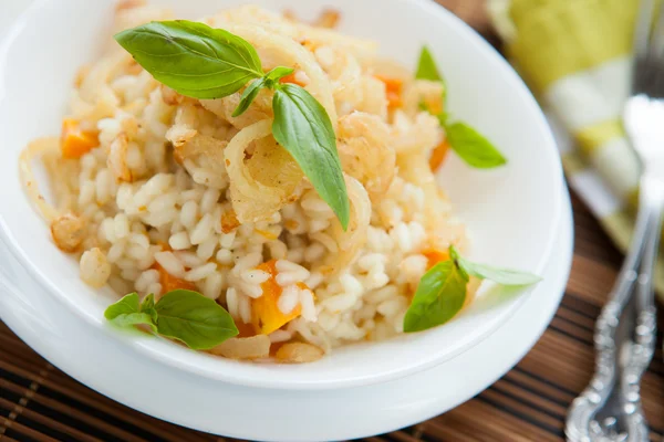 Risotto met pompoen en krokant uien in een witte kom — Stockfoto