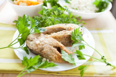 yeşillikleri ile beyaz bir tabak kızarmış balık iki adet