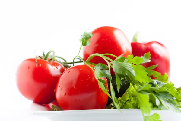 Verse tomaten en peterselie op witte plaat close-up — Stockfoto