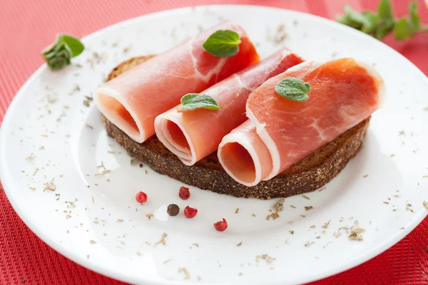 Segmenten van heerlijke ham gerold in een buis op een plaat — Stockfoto