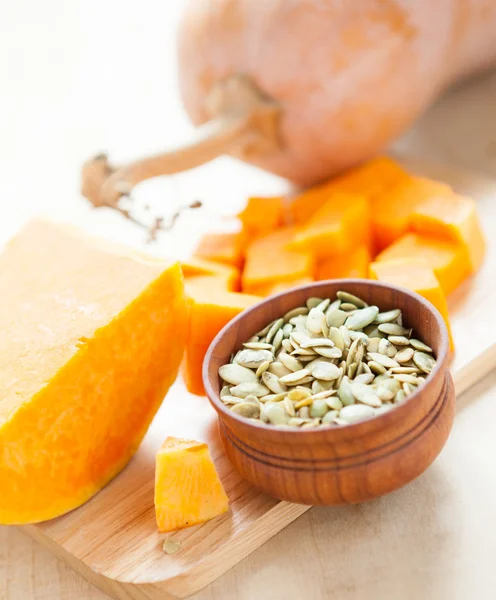 Whole pumpkin, its seeds, pieces on the board — Stock Photo, Image