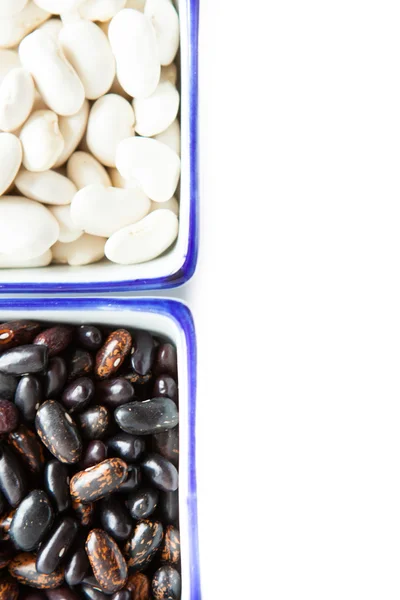 Weiße und schwarze Bohnen in einem Behälter auf weißem Hintergrund — Stockfoto