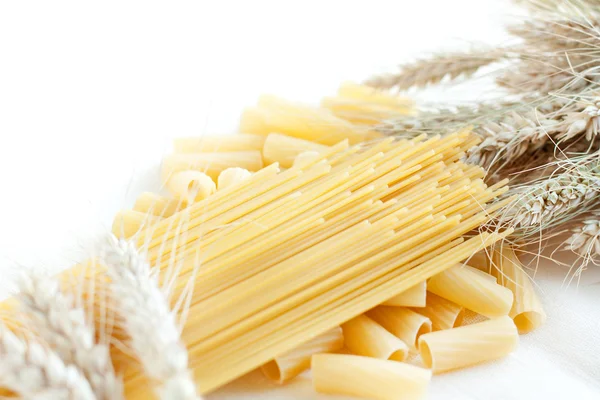 Uncooked pasta and spaghetti with wheat ears — Stock Photo, Image