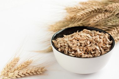 Beyaz bir kase ve kulak buğday ham flakes