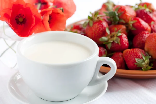 果実の背景に白いカップの牛乳 — ストック写真