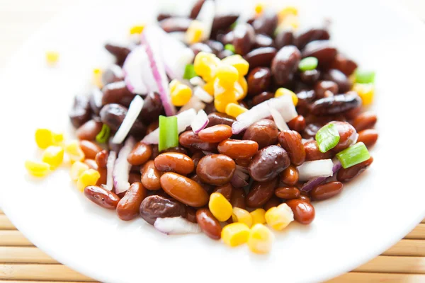 Gekochte Bohnen und Mais und Zwiebeln auf einem weißen Teller — Stockfoto