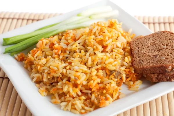 Rice with green onions and brown bread on a white square plate — Stock Photo, Image