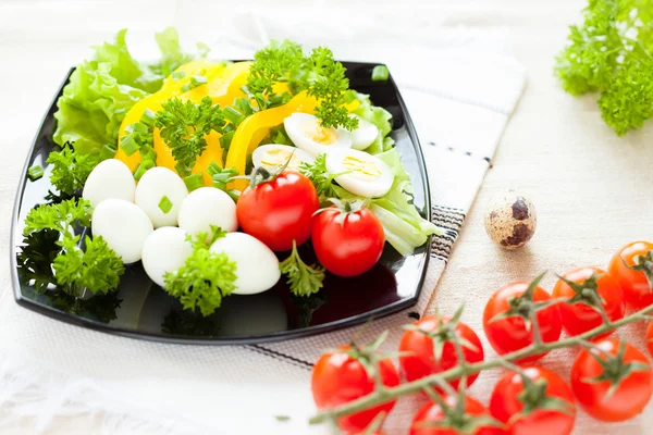 Salad with fresh vegetables and quail eggs on a square plate — Stock Photo, Image