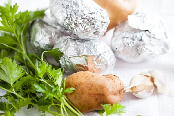 Ruwe aardappelen en Groenen en folie — Stockfoto
