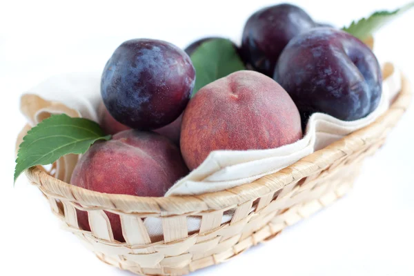 Ripe peaches and plums in the basket — Stock Photo, Image