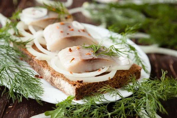 Salted herring fillet on black crusty bread — Stock Photo, Image