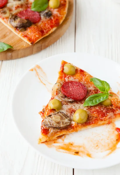 Appetitoso pezzo di pizza su un piatto bianco — Foto Stock