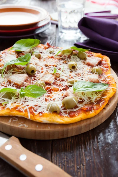 Homemade pizza with bacon on the board and knife — Stock Photo, Image