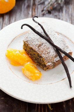 haşhaş tohumu pasta üzerinde beyaz bir tabak turuncu bir dilim