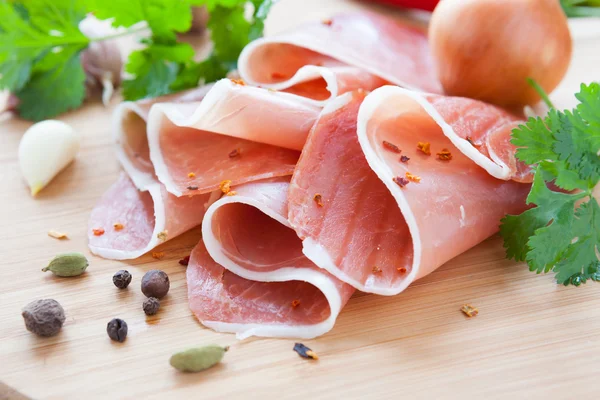 Thin slices of ham on a wooden surface — Stock Photo, Image