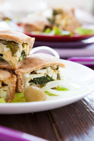 Egg-spinach pie cut into pieces on white dish — Stock Photo, Image