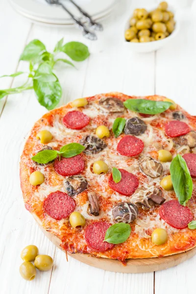 Round pizza with slices of salami on white boards — Stock Photo, Image