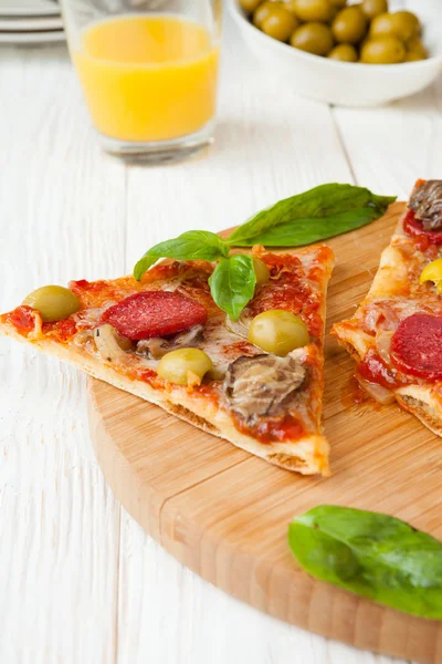 Segmenten van pizza met salami en basilicum — Stockfoto