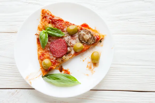 Plak van pizza met salami en basilicum op wit bord — Stockfoto