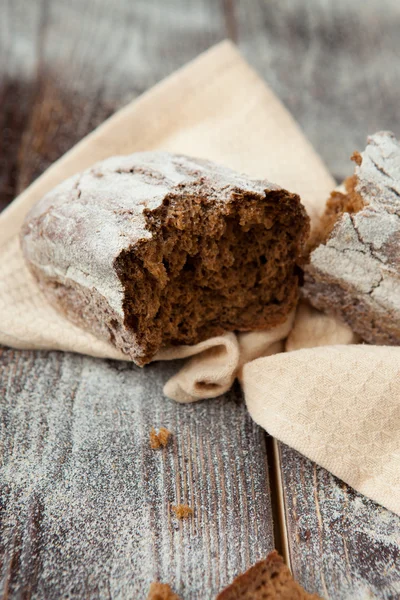 Medio pan de grano entero sobre una mesa de madera — Foto de Stock