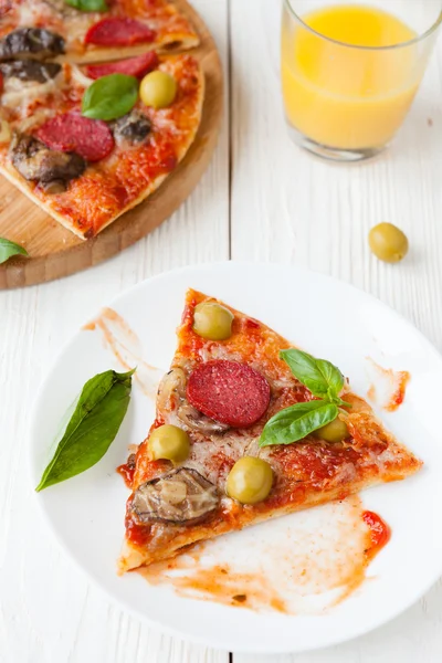 Plak van pizza op een plaat en pizza op achtergrond — Stockfoto